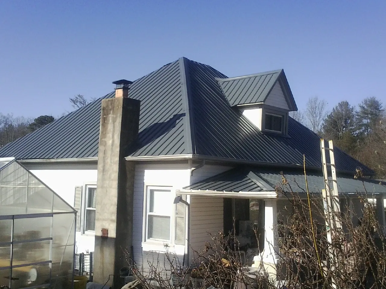 Dark blue standing seam metal roof on a white farmhouse with dormer — Slate & Tile Roof Repair by Roofing Brothers in Finksburg