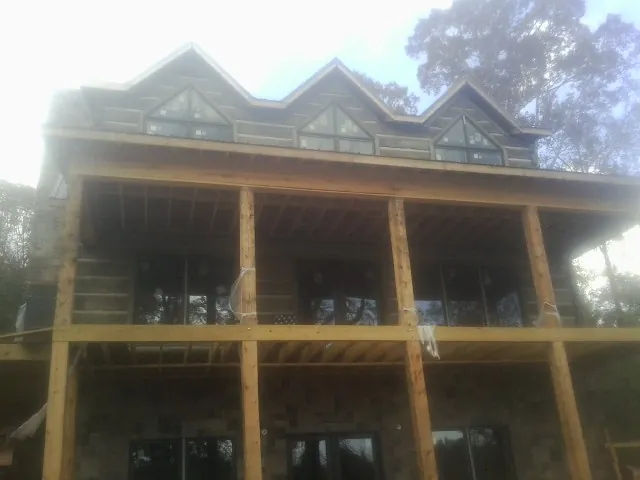 Dormers and porch framing on a large log home under construction — Roof Coating work by our crew in Finksburg