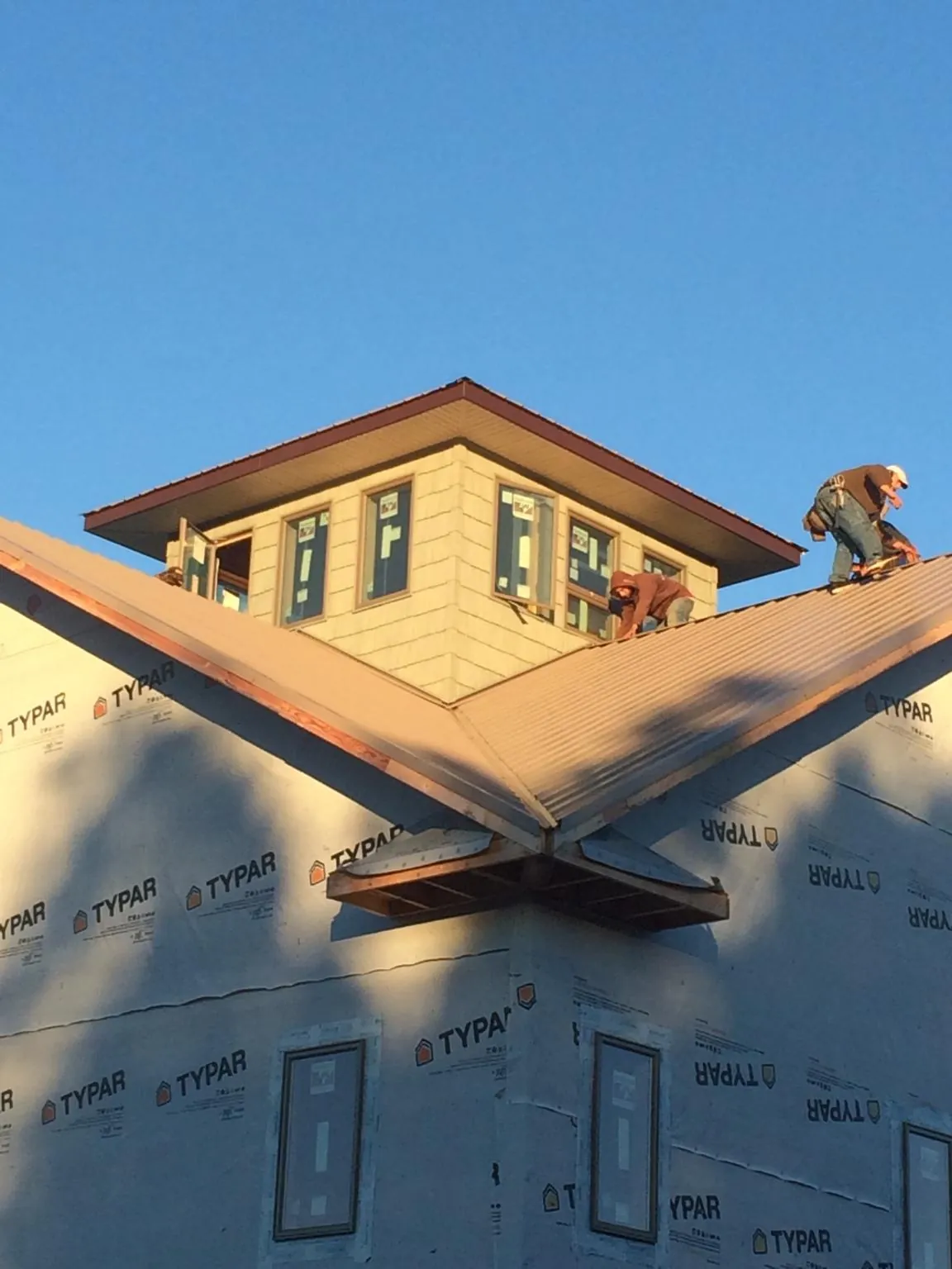 Roofers working around a rooftop cupola on a new metal roof at sunset — Roof Waterproofing in Finksburg by Roofing Brothers